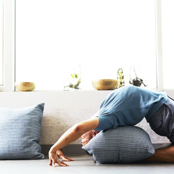 Picture of a man using a pillow to do foam rolling exercises at home