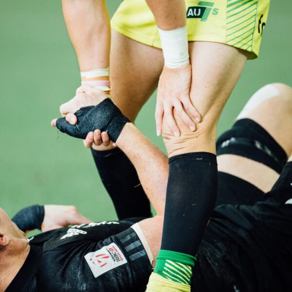 Picture of two soccer players, one is lying down and the other is helping him up with a hand on his knee to suggest there is ACL rehabilitation underway