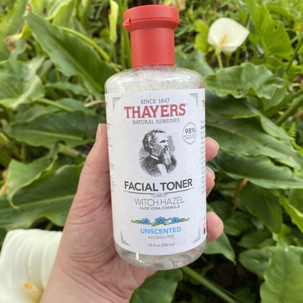 Picture of Thayers toner being held with green plants in the background