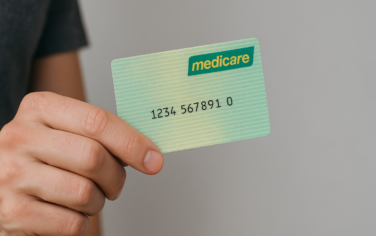 Picture of a man holding a medicare card, giving hime access to Extended Medicare Safety Net